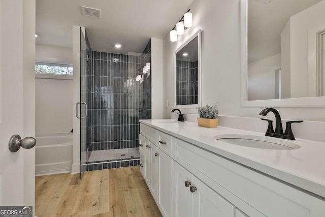 bathroom with hardwood / wood-style floors, vanity, and plus walk in shower