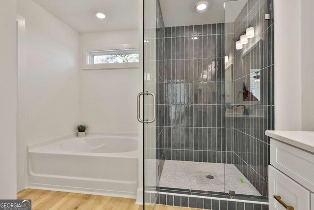 bathroom with wood-type flooring, vanity, and independent shower and bath