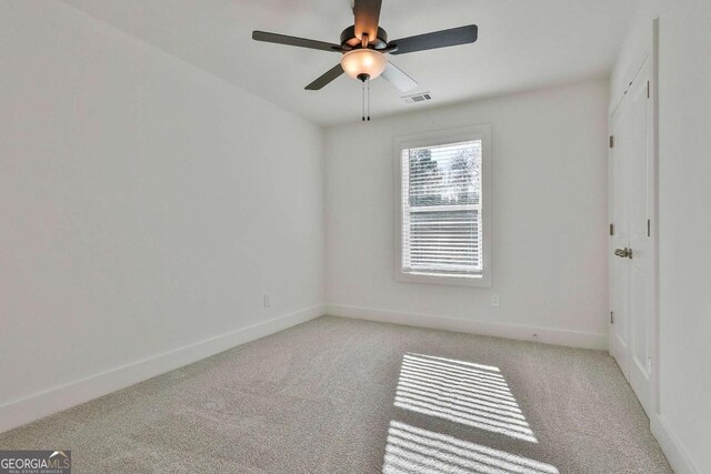 carpeted spare room featuring ceiling fan