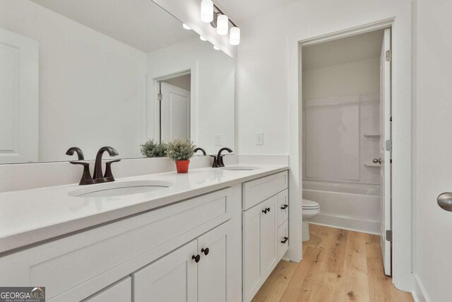 full bathroom featuring hardwood / wood-style floors, vanity,  shower combination, and toilet