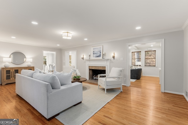 living room featuring light wood-type flooring, ornamental molding, and a brick fireplace