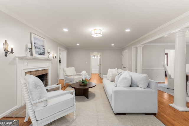 living room featuring light wood-type flooring, ornate columns, and ornamental molding