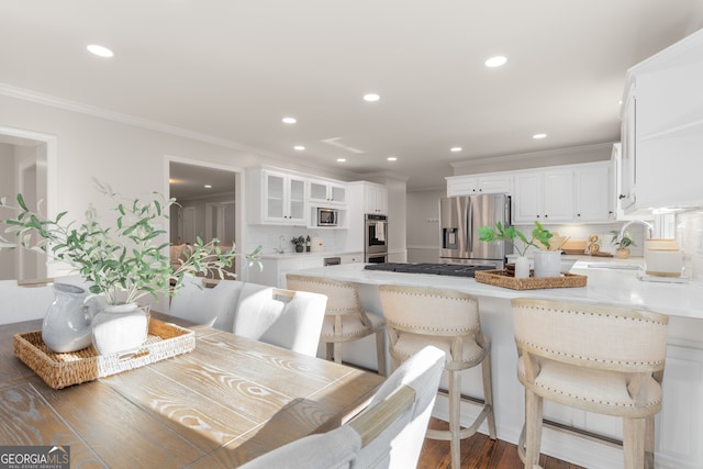 dining area featuring sink, dark wood-type flooring, and ornamental molding