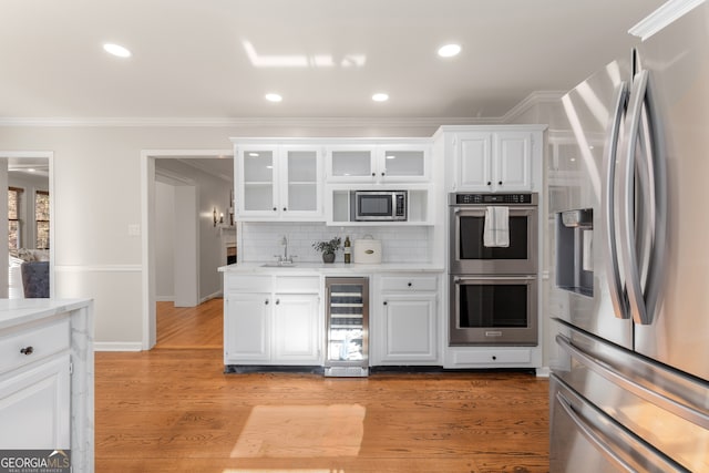 kitchen with decorative backsplash, white cabinetry, stainless steel appliances, and wine cooler