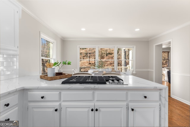 kitchen with stainless steel gas stovetop, light stone countertops, and white cabinetry