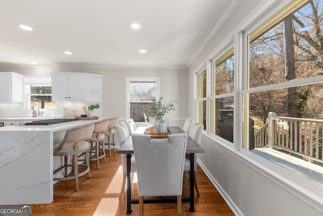 dining room with crown molding and light hardwood / wood-style flooring