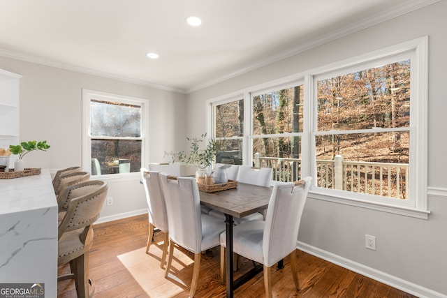 dining room with crown molding and light hardwood / wood-style flooring