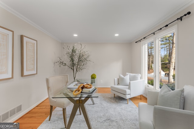 office with light hardwood / wood-style floors, crown molding, and a healthy amount of sunlight