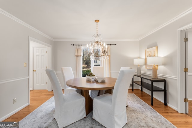 dining room with a notable chandelier, light hardwood / wood-style floors, and crown molding