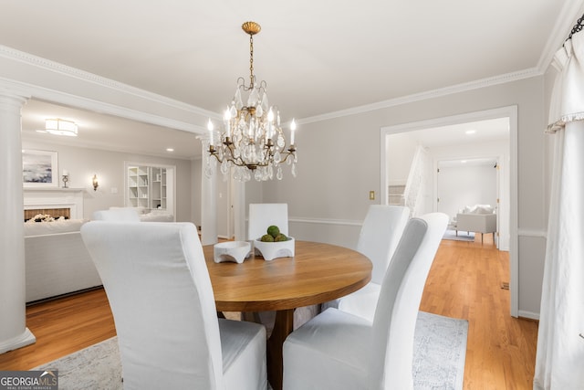 dining space with light hardwood / wood-style floors, an inviting chandelier, and crown molding