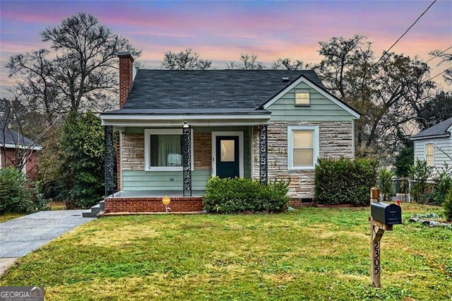 bungalow-style home featuring a porch and a yard