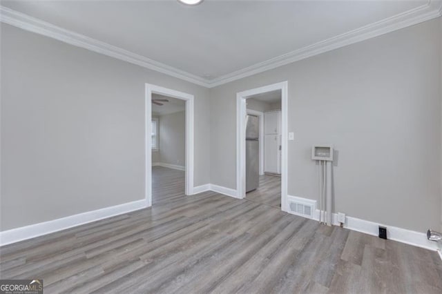 unfurnished room featuring light wood-type flooring and crown molding