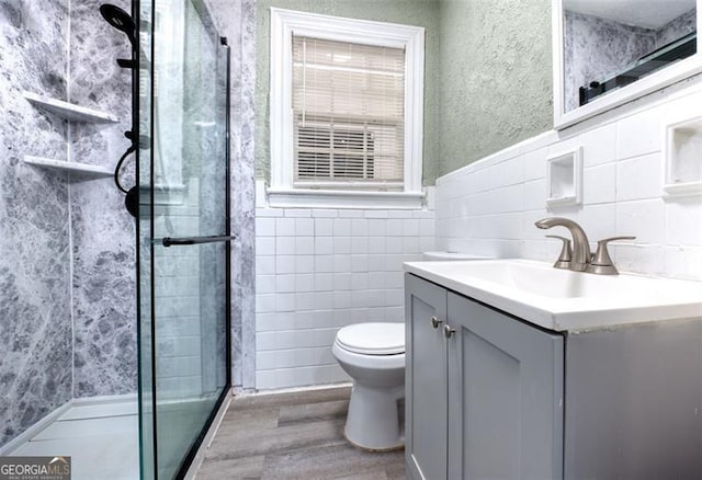 bathroom with toilet, vanity, a shower with shower door, and hardwood / wood-style flooring