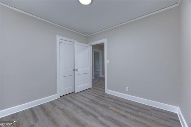 unfurnished room with light hardwood / wood-style floors and crown molding