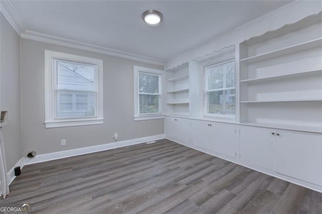 spare room with crown molding, plenty of natural light, built in features, and light hardwood / wood-style flooring