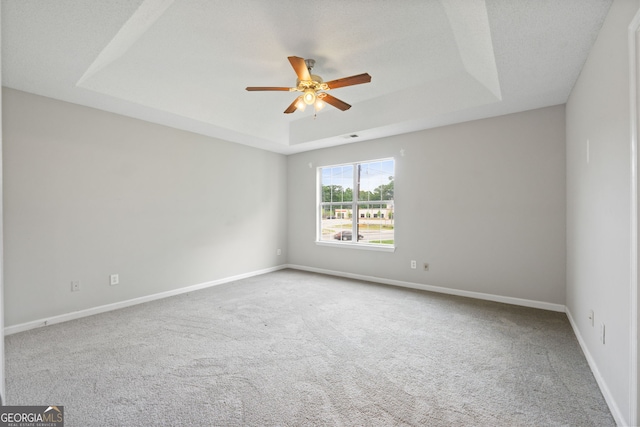 carpeted empty room with a textured ceiling, a raised ceiling, and ceiling fan