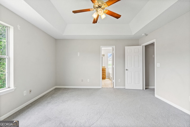 empty room featuring carpet floors, a tray ceiling, plenty of natural light, and ceiling fan