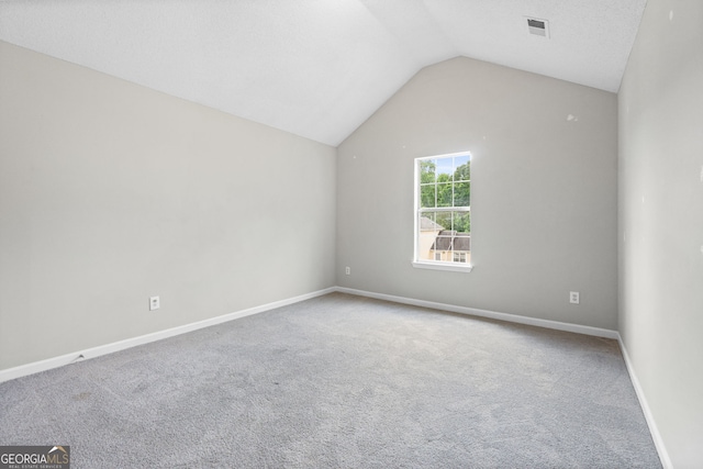 carpeted empty room featuring vaulted ceiling