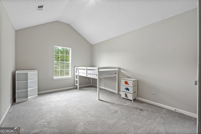 unfurnished bedroom featuring a textured ceiling, carpet floors, and lofted ceiling