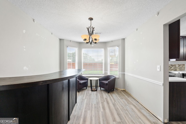 sitting room featuring a chandelier, a textured ceiling, and light wood-type flooring