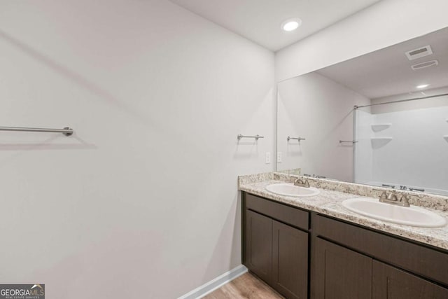 bathroom with hardwood / wood-style floors, vanity, and walk in shower