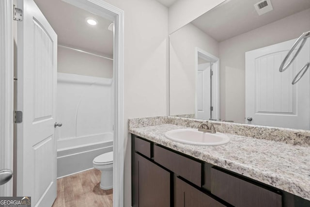 full bathroom featuring vanity, hardwood / wood-style flooring, toilet, and tub / shower combination