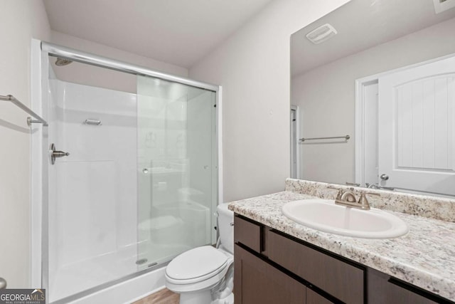 bathroom featuring vanity, toilet, and a shower with door