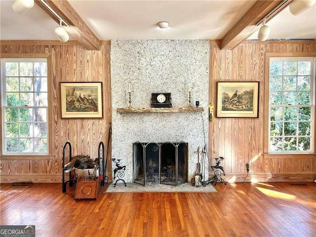 living room featuring beam ceiling, a fireplace, and wooden walls