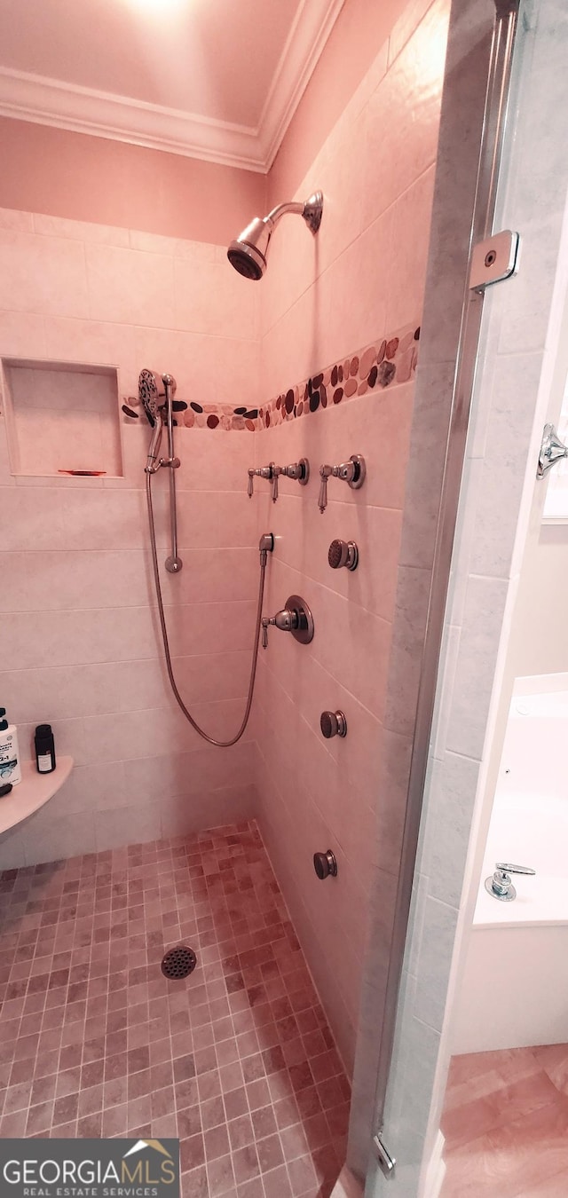 bathroom with a tile shower and ornamental molding