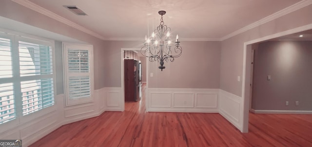 unfurnished dining area featuring ornamental molding, light wood-type flooring, and an inviting chandelier