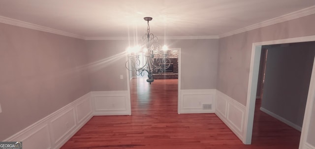 unfurnished dining area featuring hardwood / wood-style floors, ornamental molding, and a chandelier