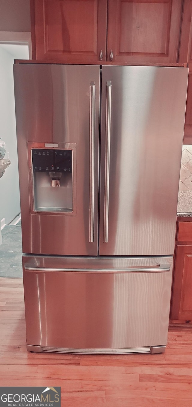 interior details with stainless steel refrigerator with ice dispenser, light hardwood / wood-style flooring, and light stone counters