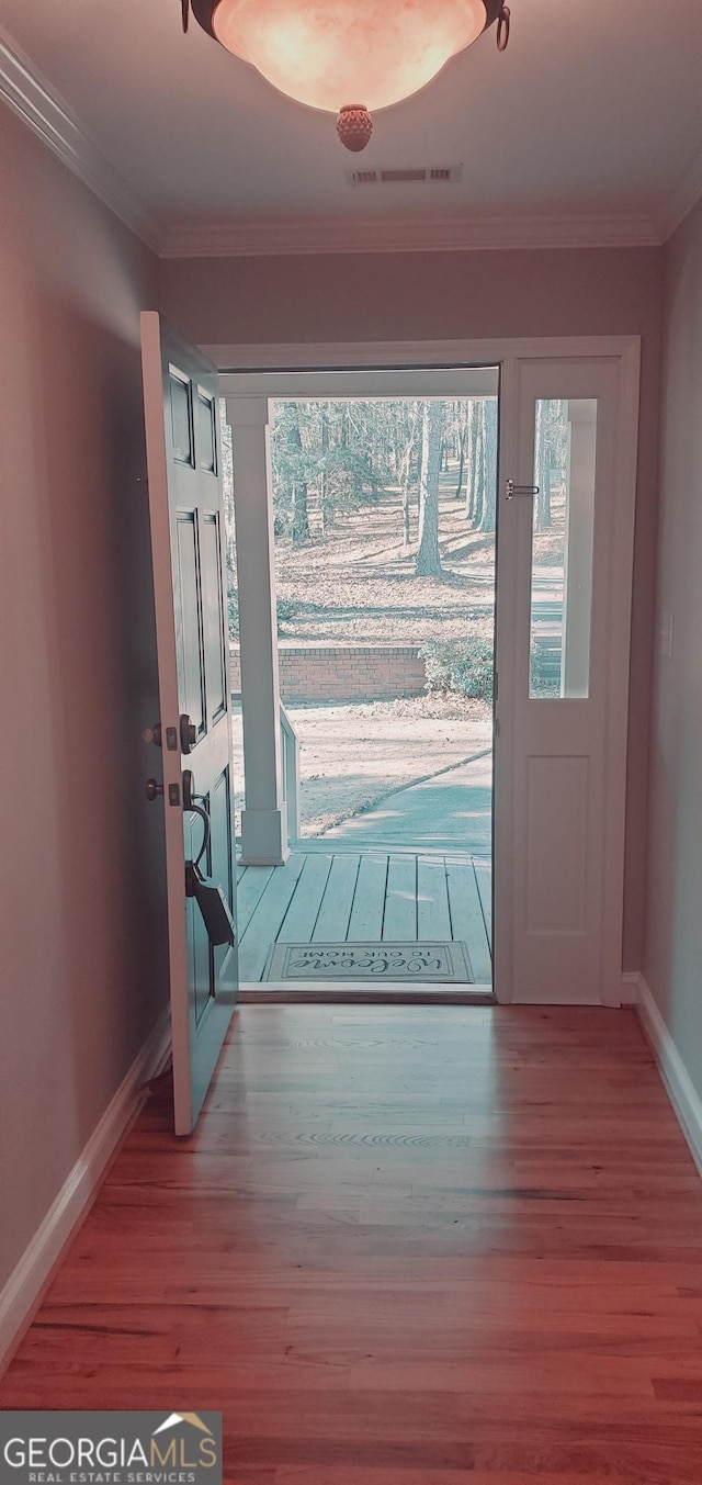 doorway to outside with wood-type flooring and crown molding