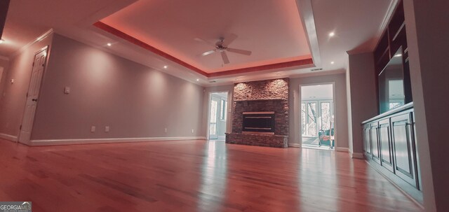 1030 Lake Haynes Dr NE, Conyers, GA 30012 - unfurnished living room with a ceiling fan, a stone fireplace, wood finished floors, a raised ceiling, and baseboards