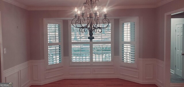 1030 Lake Haynes Dr NE, Conyers, GA 30012 - unfurnished dining area featuring a chandelier, wood finished floors, a decorative wall, and a wainscoted wall