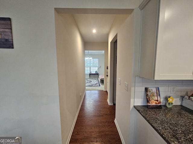 hallway featuring dark hardwood / wood-style floors and a chandelier