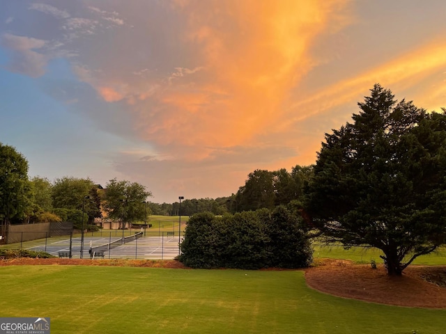 surrounding community with tennis court and a yard