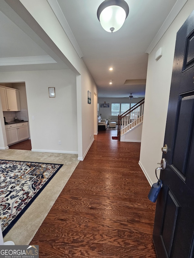 hallway featuring ornamental molding and dark colored carpet