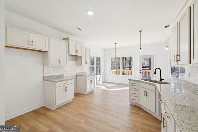 kitchen featuring hanging light fixtures, tasteful backsplash, sink, and white cabinets