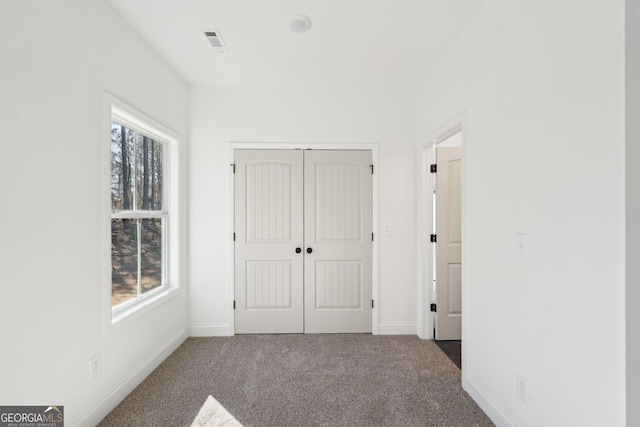 unfurnished bedroom with dark carpet and a closet