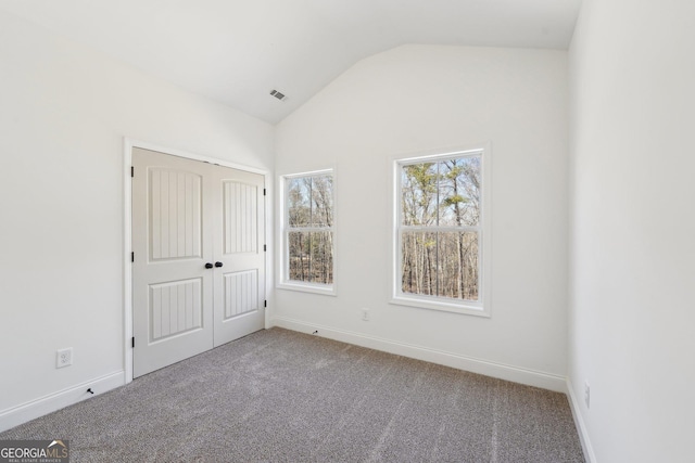 unfurnished bedroom with lofted ceiling, carpet flooring, and a closet