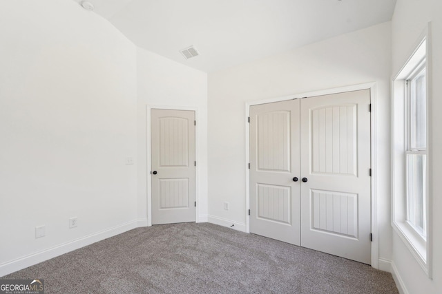 unfurnished bedroom with vaulted ceiling, light carpet, and a closet