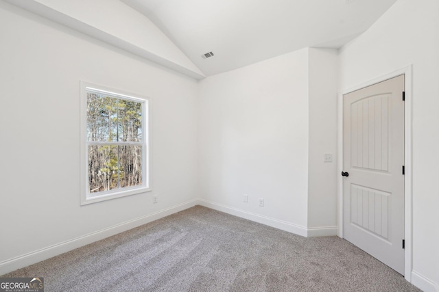 carpeted empty room featuring lofted ceiling