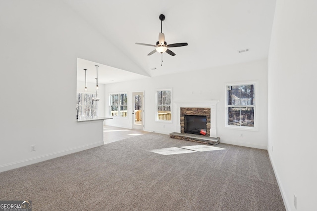 unfurnished living room featuring ceiling fan, a stone fireplace, light colored carpet, and high vaulted ceiling