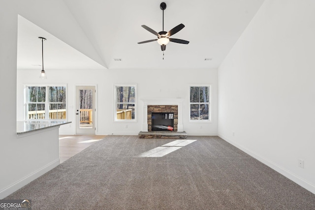 unfurnished living room with lofted ceiling, ceiling fan, a fireplace, and light carpet