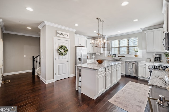 kitchen featuring appliances with stainless steel finishes, white cabinetry, hanging light fixtures, and a center island