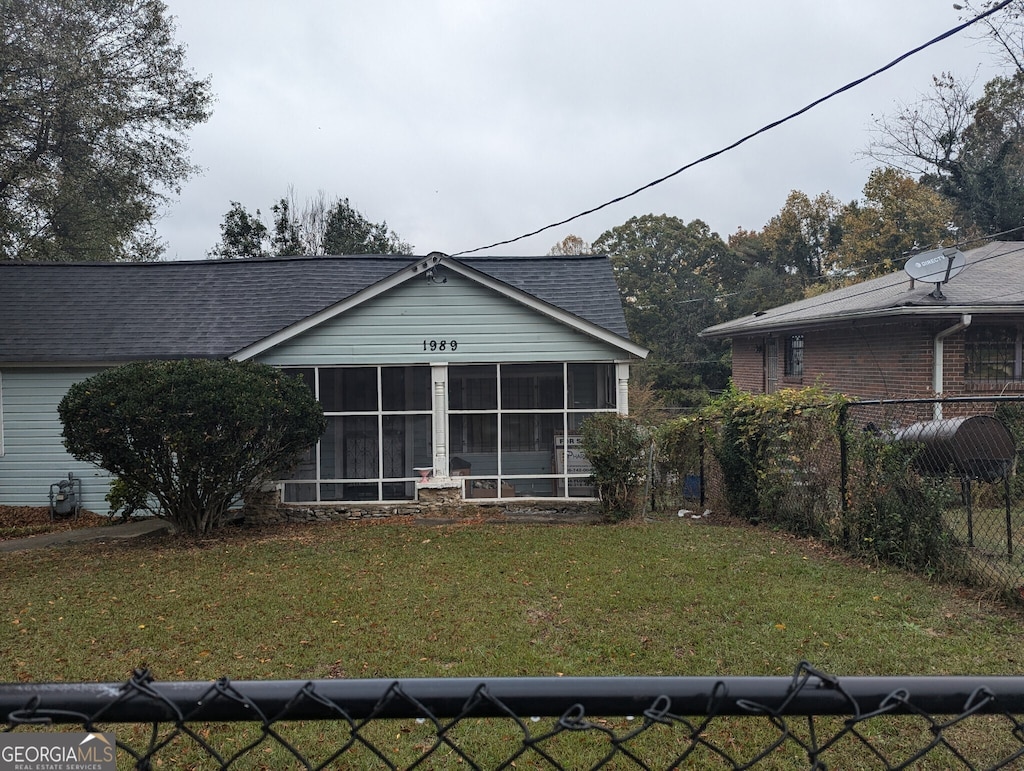 rear view of house featuring a lawn and a sunroom