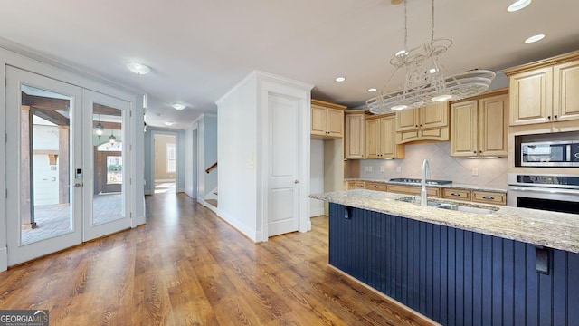 kitchen featuring light stone countertops, french doors, decorative light fixtures, appliances with stainless steel finishes, and hardwood / wood-style flooring