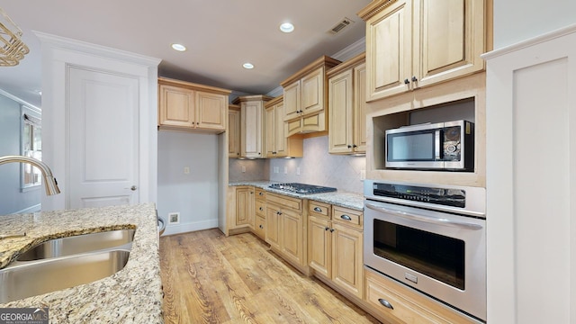 kitchen featuring sink, light stone counters, light hardwood / wood-style flooring, light brown cabinetry, and appliances with stainless steel finishes