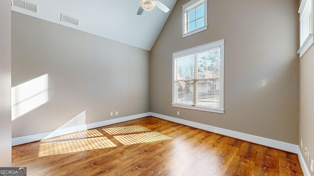 empty room with ceiling fan, high vaulted ceiling, and wood-type flooring